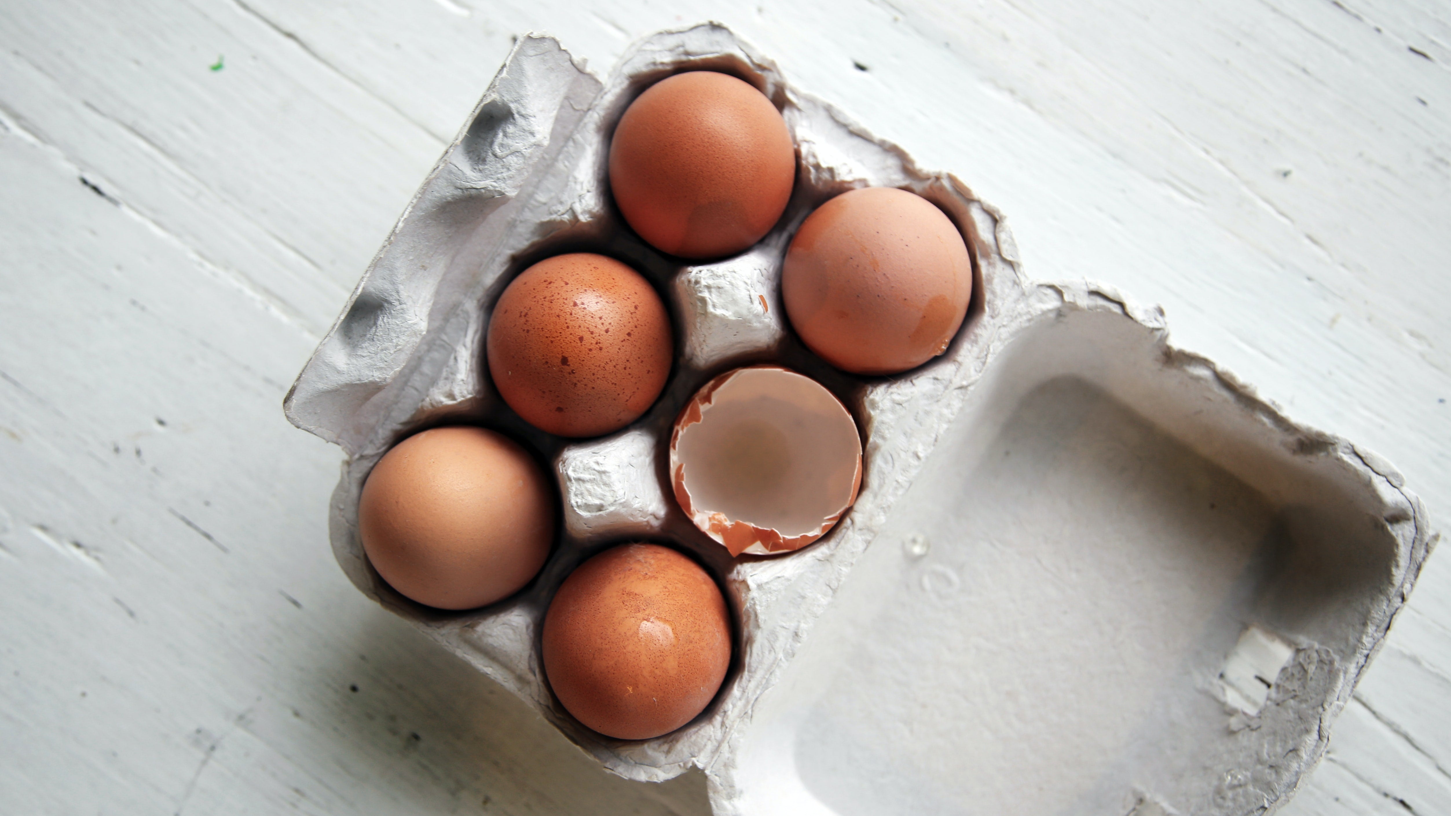 A carton of six eggs, one cracked, representing food myths about eggs.