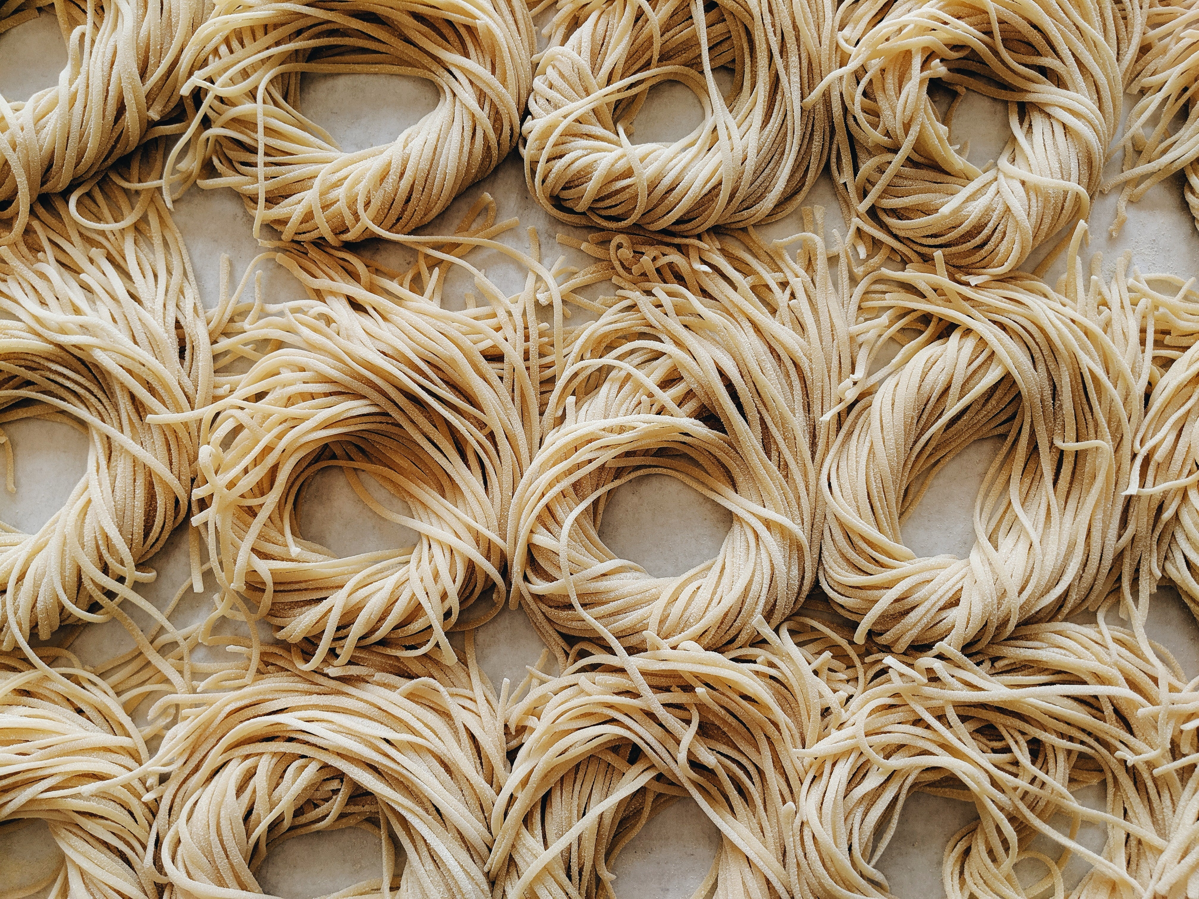 Close-up of uncooked pasta nests on a surface.