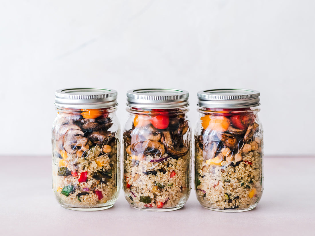 Three jars filled with quinoa, vegetables, and nuts, showcasing high-fiber meal options.