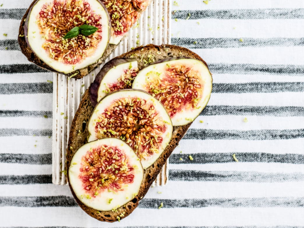 Sliced figs on a piece of bread with a striped background