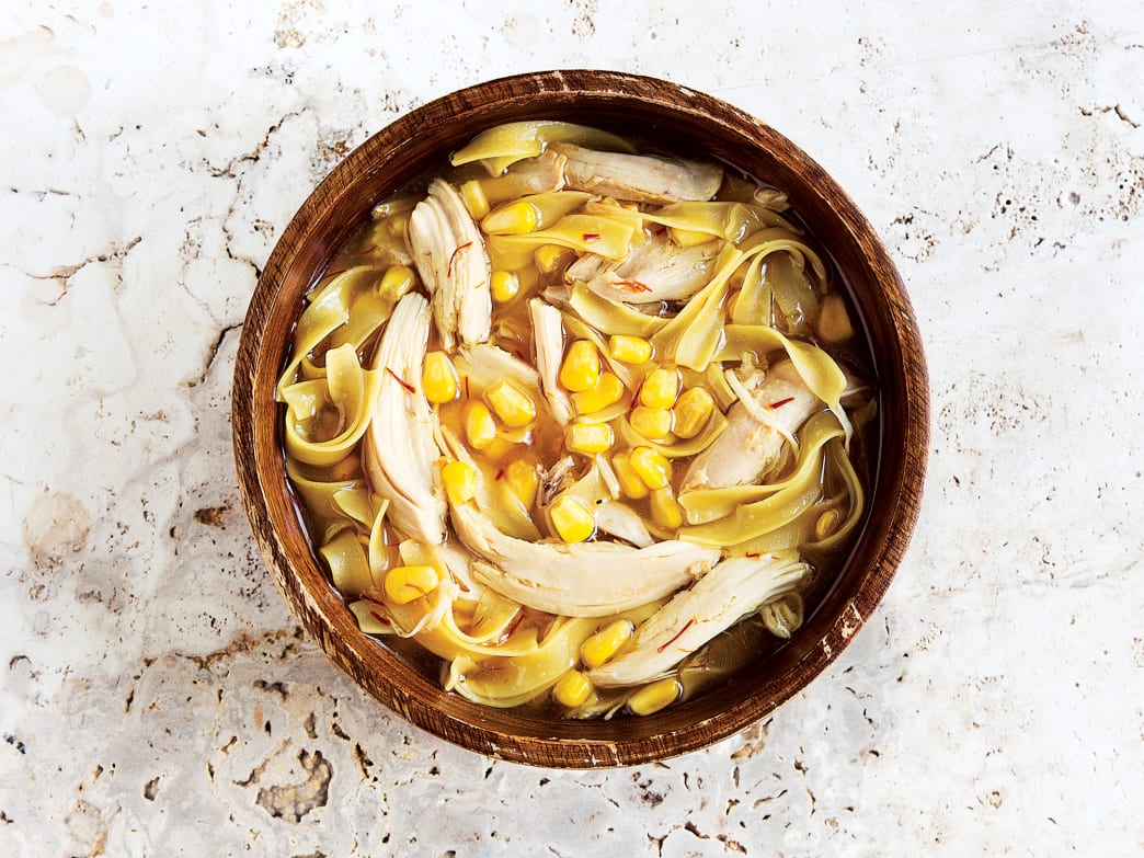 Bowl of roasted chicken, corn, and saffron soup with egg noodles