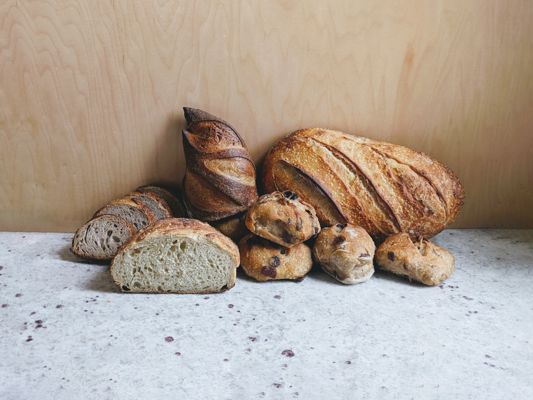 An assortment of various breads including sourdough, whole grain, and rolls on a countertop.
