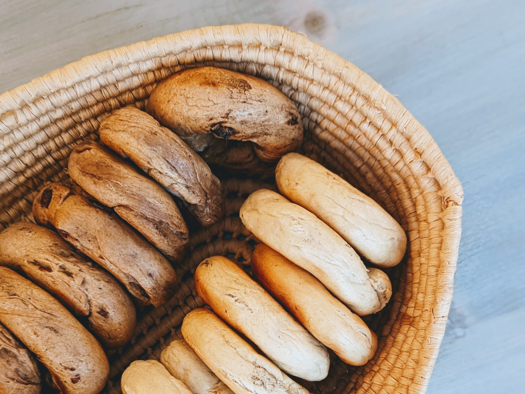 A basket containing various bagels, some dark and some light in color.