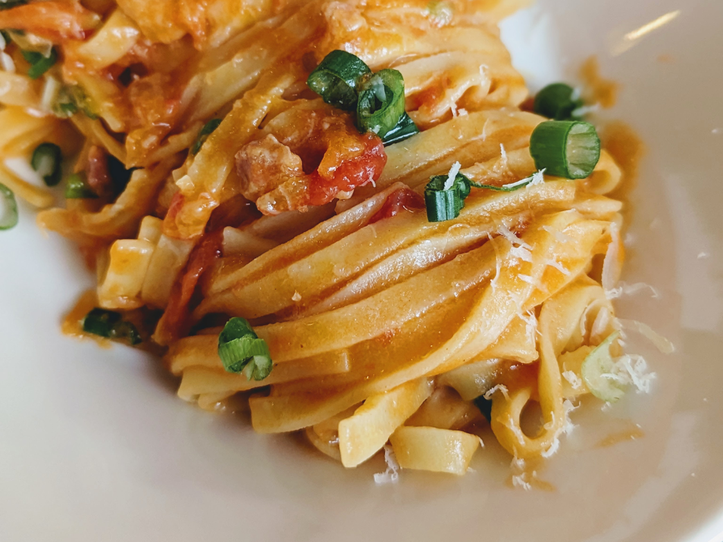 Close-up of fettuccine pasta with sauce and green onions