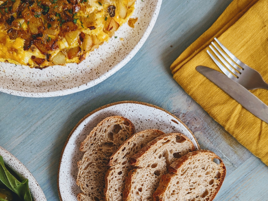 Sliced sourdough rye bread on a plate, with a fork and napkin nearby