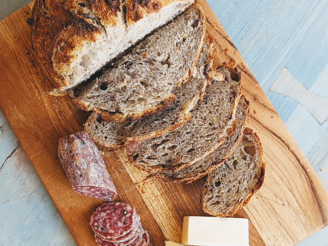 Sliced whole grain bread on a wooden board with salami and cheese
