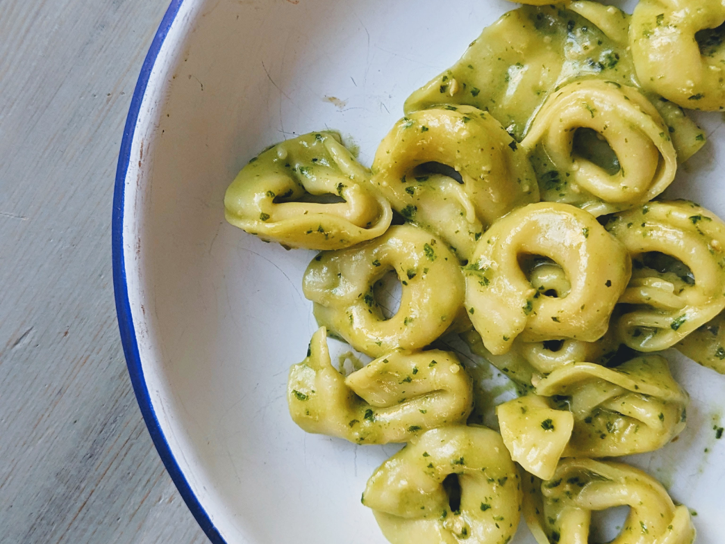 A bowl of tortellini pasta with pesto sauce