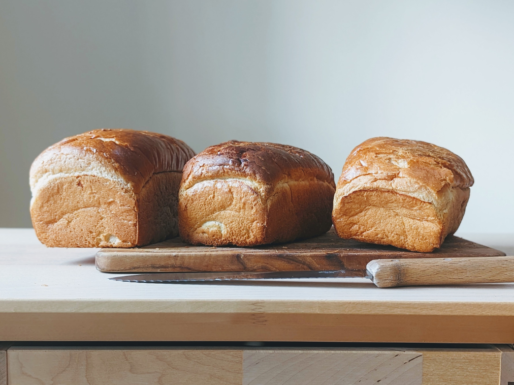 Three loaves of bread on a cutting board