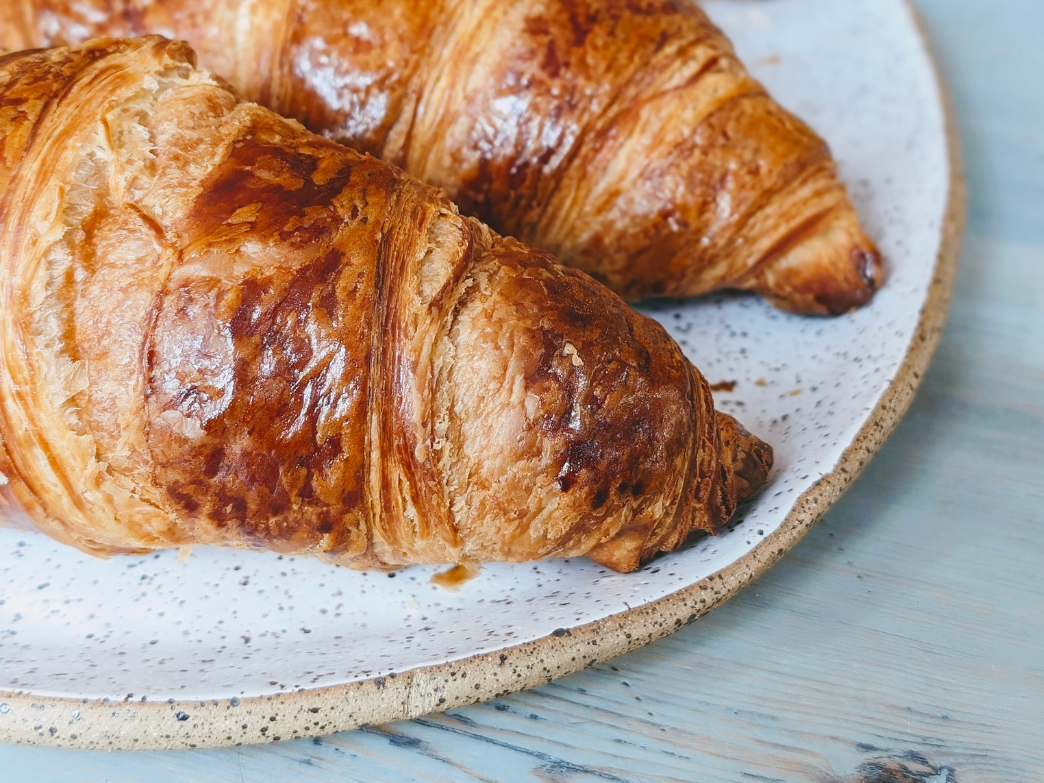 Close-up of two golden-brown vegan croissants on a speckled plate