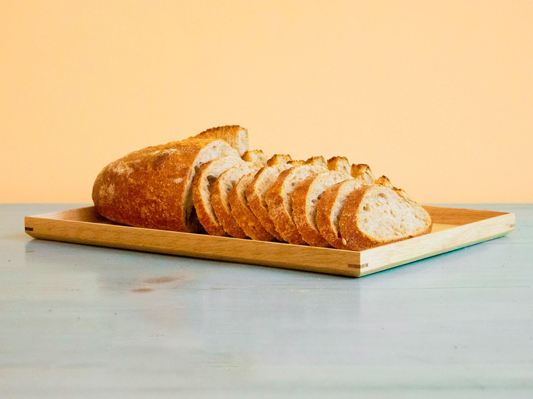 Sliced dairy-free bread on a wooden board against an orange background