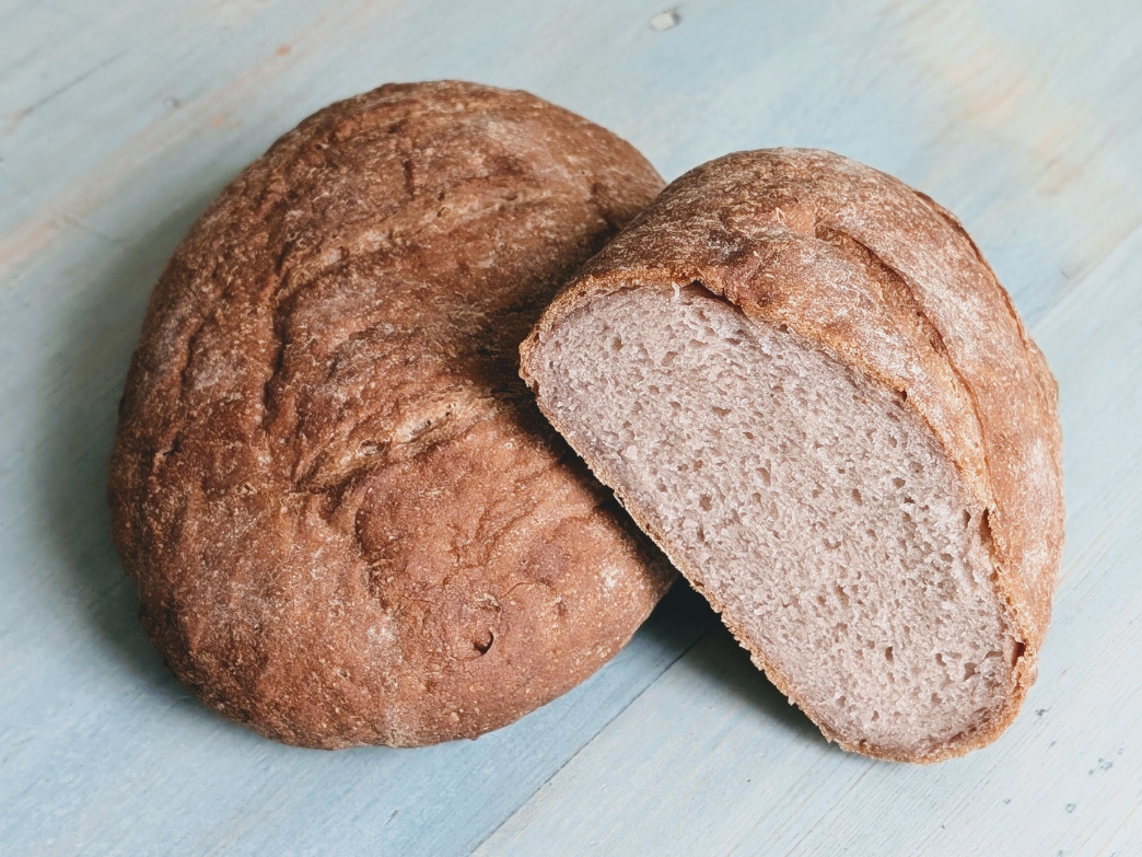 A round loaf of gluten-free bread, sliced to show the inside texture.