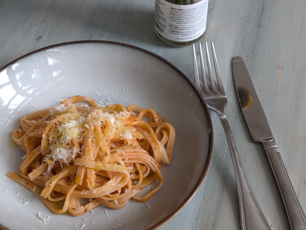 Plate of pasta with cheese, fork and knife on the side