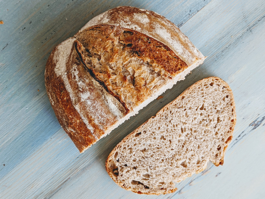 Top-down view of a sliced sourdough loaf showing crusty golden exterior and open airy crumb on a blue wooden surface