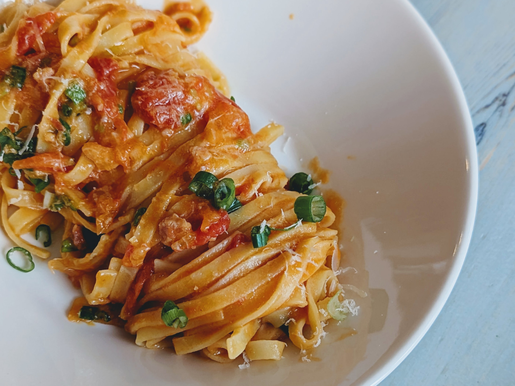Plate of pasta with tomatoes and green onions