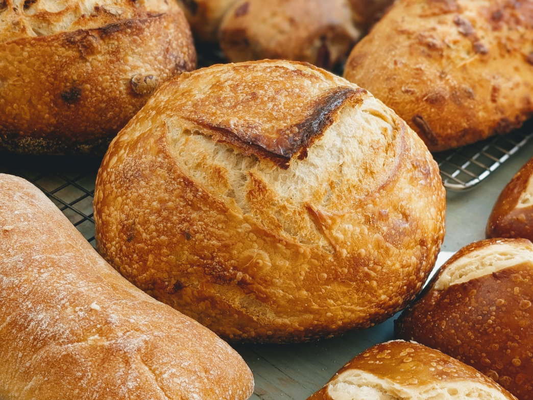 Assorted crusty loaves (sourdough and ciabatta) cooling on wire racks