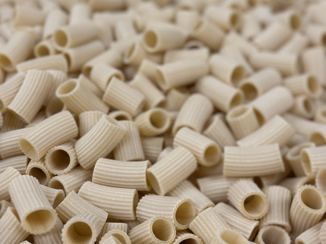 Close-up of uncooked short ridged tubular pasta (rigatoni) filling the frame.