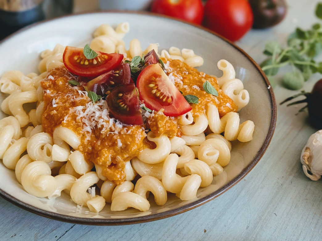 Cavatappi pasta with creamy tomato-ricotta sauce, grated Parmesan and cherry tomato wedges garnished with oregano