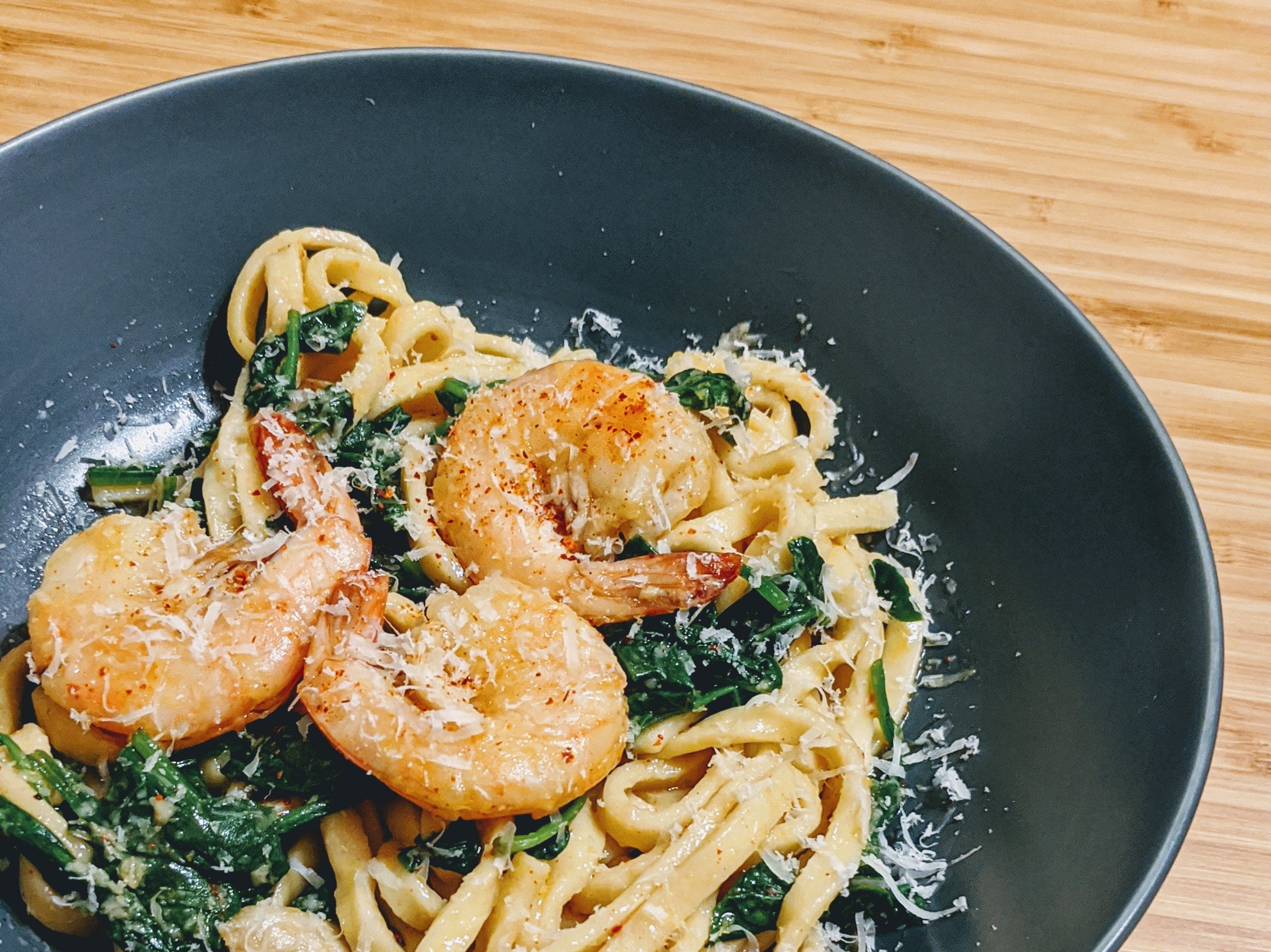 Plate of linguine with shrimp and spinach, topped with parmesan cheese