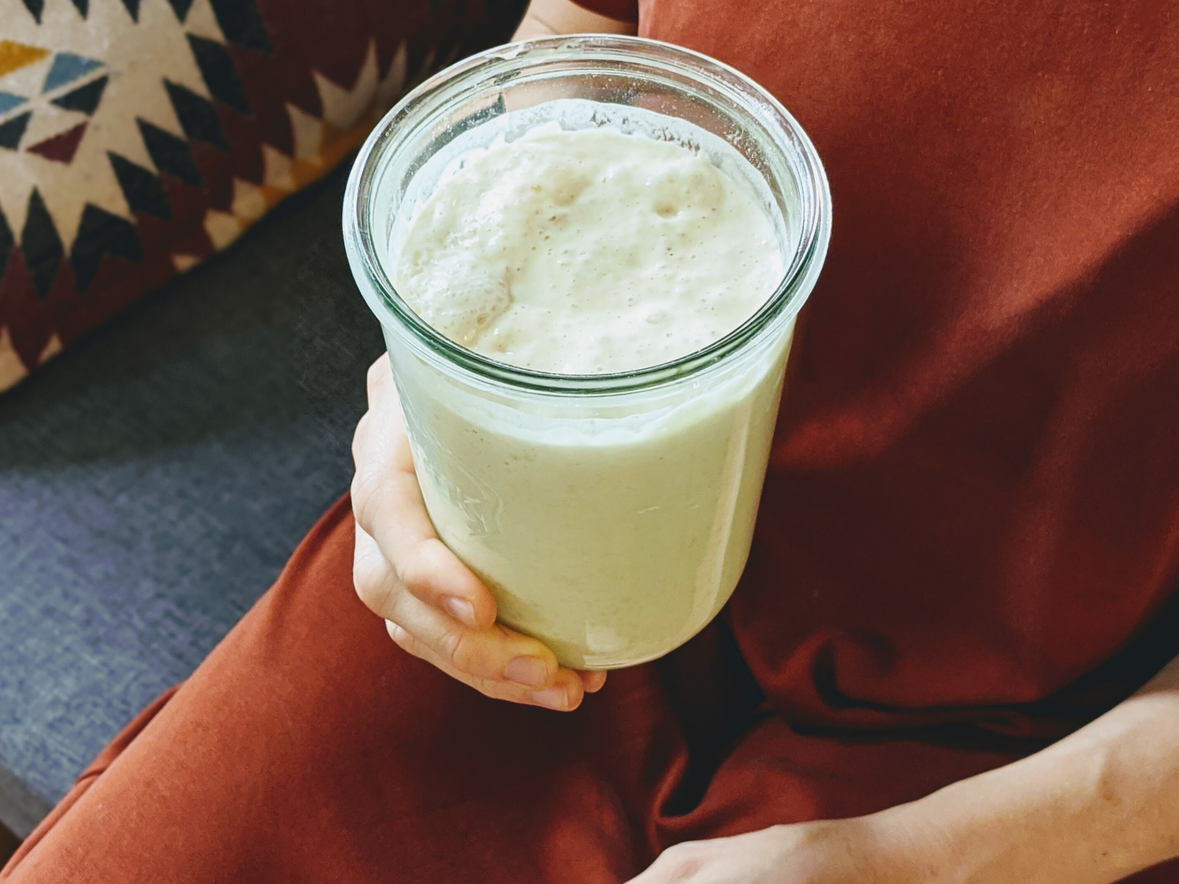 A person holding a jar of bubbly sourdough starter