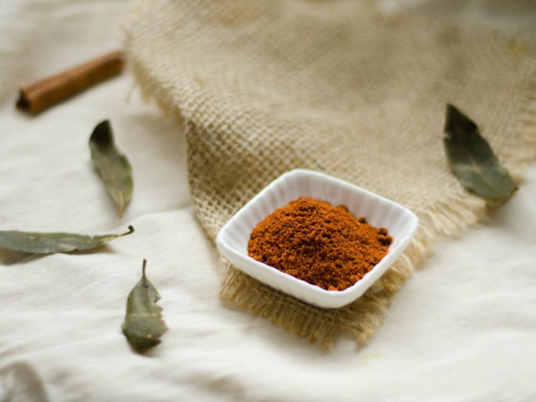 Bowl of ground spice on a cloth with leaves