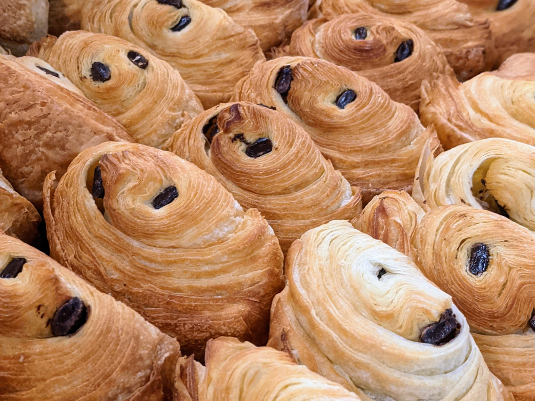 Close-up of various chocolate croissants and pastries with flaky layers
