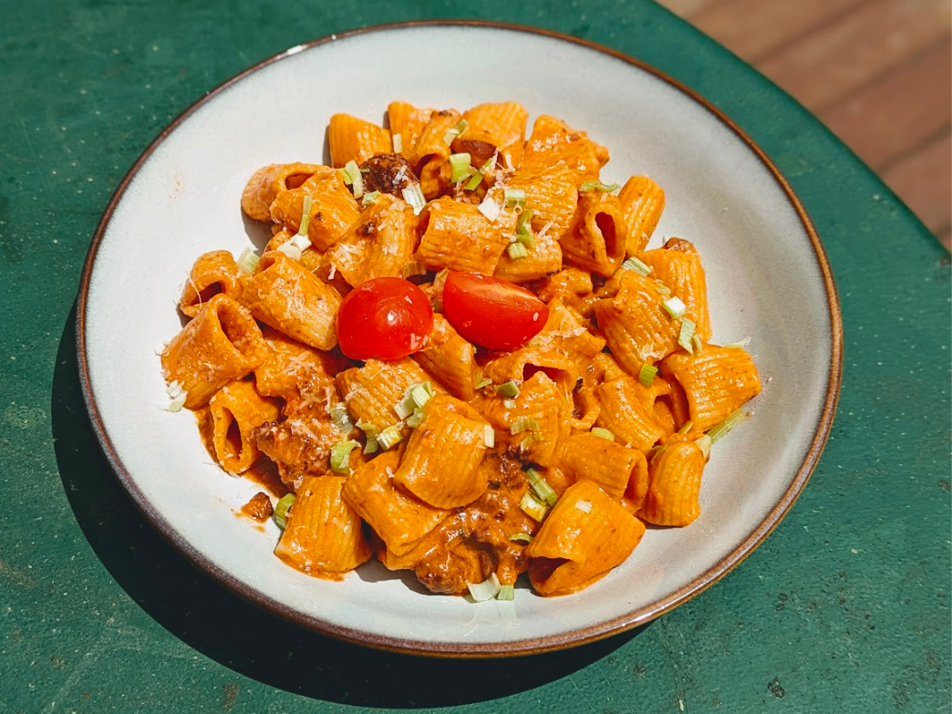 A plate of pasta with cherry tomatoes and herbs.