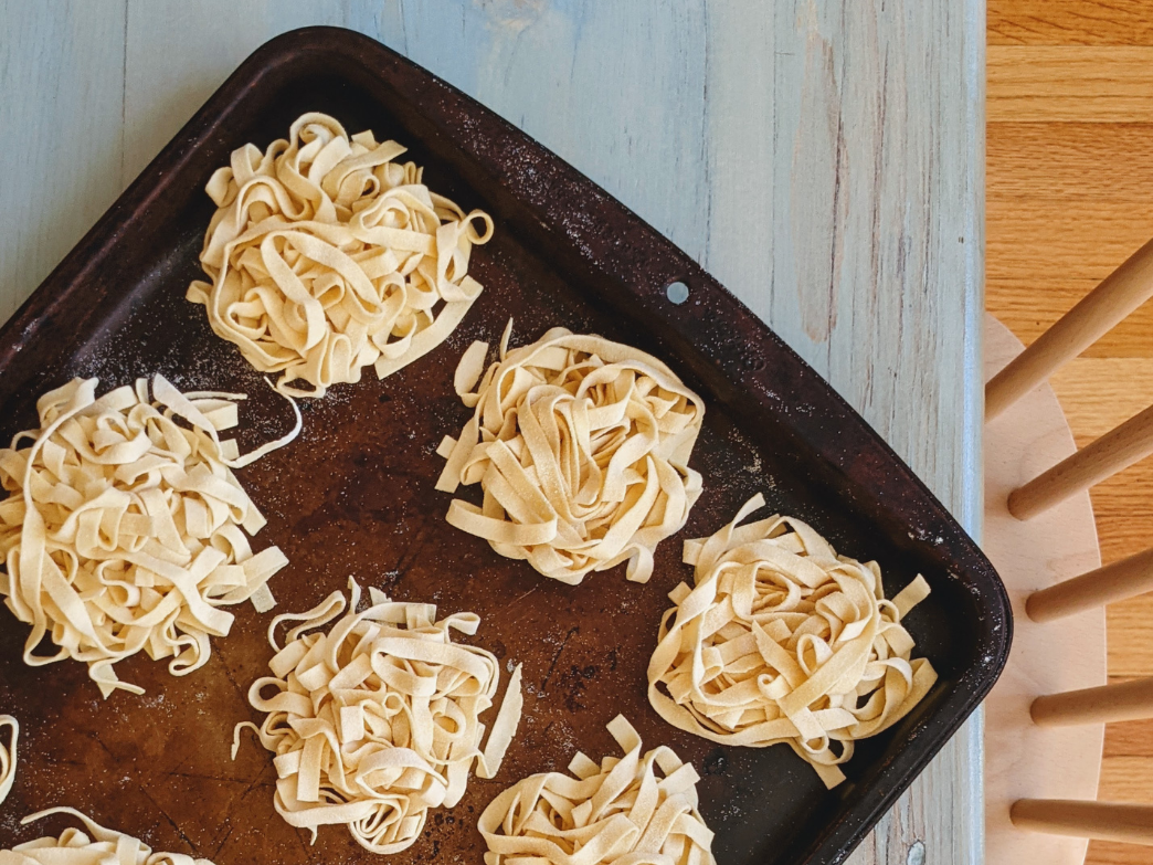 Fresh fettuccine pasta nests arranged on a baking tray.