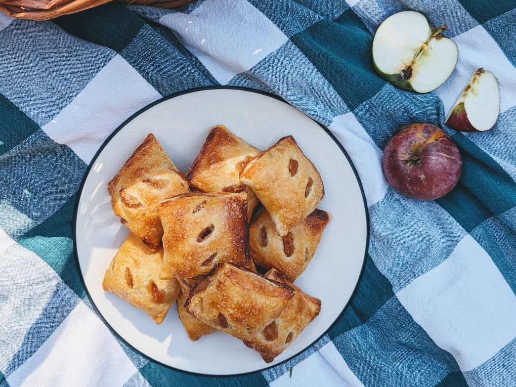 A plate of pastries with apples on a checkered tablecloth.