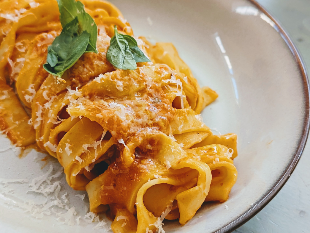 A plate of fettuccine pasta topped with basil and cheese.