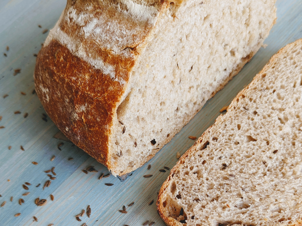 Close-up of sliced whole grain bread with seeds on a wooden surface.