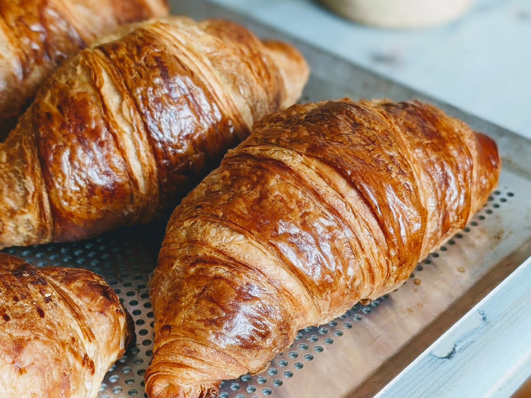 Golden-brown, flaky croissants on a baking tray