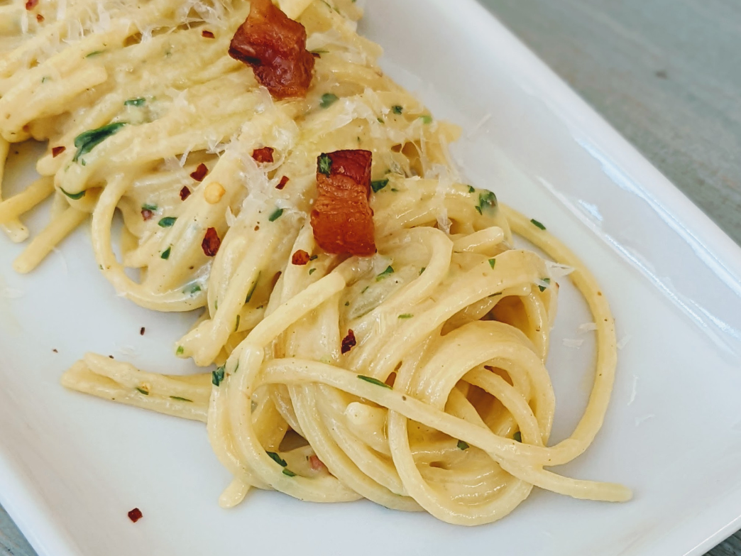 Plate of creamy pasta with bacon and herbs