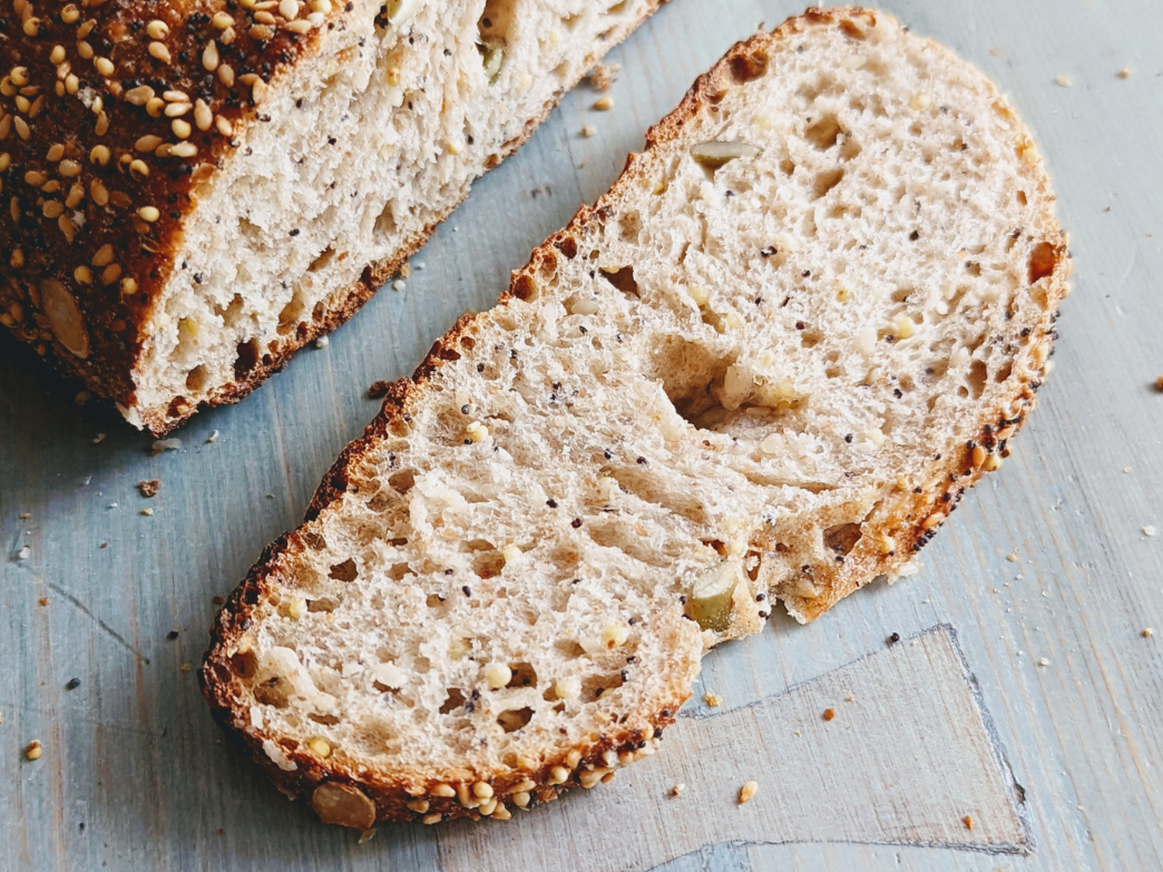 Close-up of a slice of whole grain bread with seeds on a wooden surface