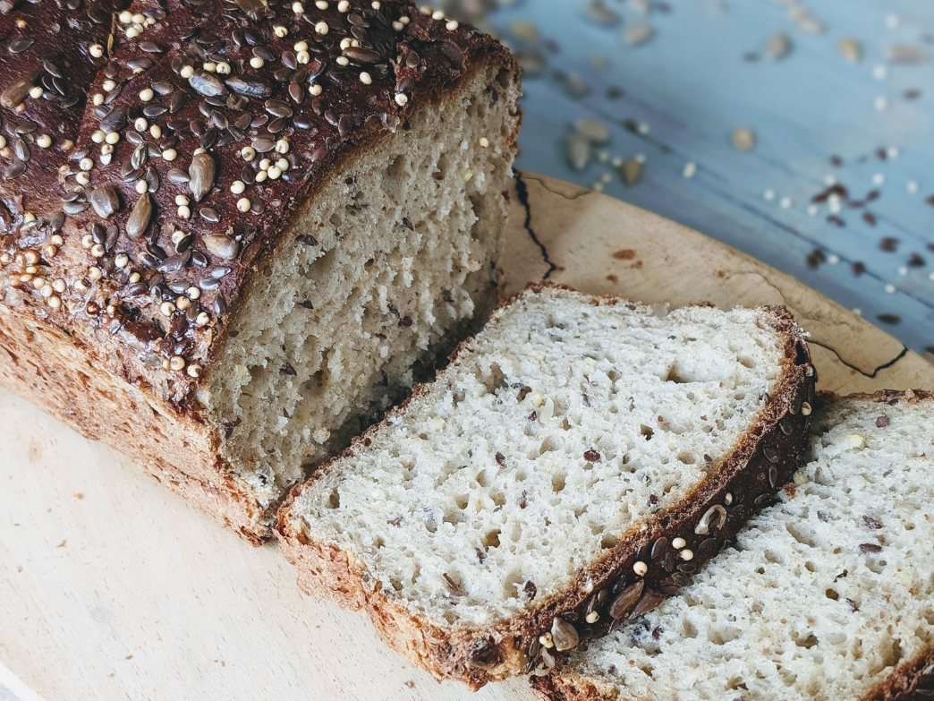 Sliced seeded loaf of bread on a wooden board