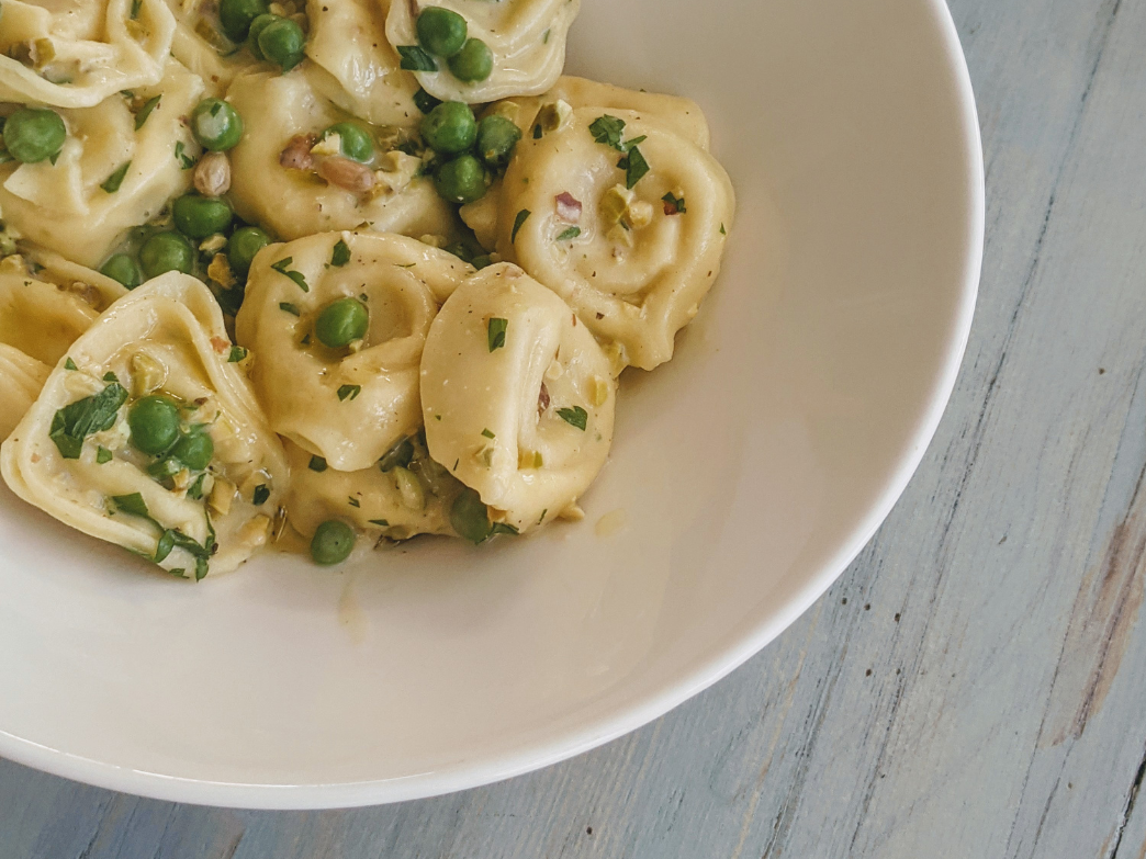 A bowl of gluten-free pasta with peas and herbs.
