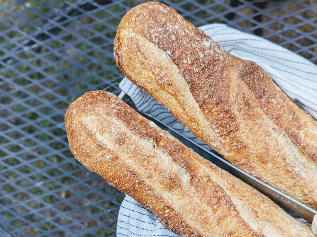Two freshly baked baguettes on a striped cloth