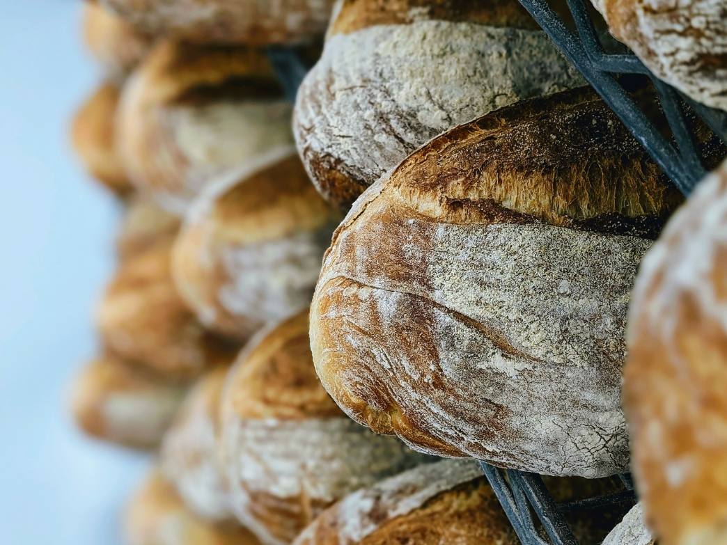 Rustic loaves of bread stacked on a metal rack with a blurred background