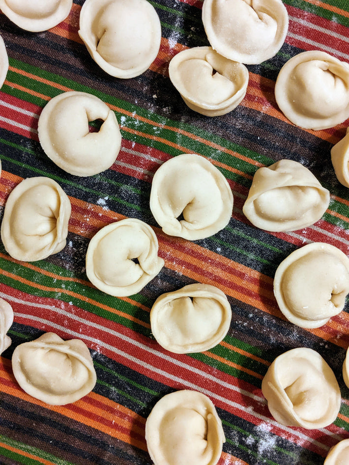 Raw cheese tortellini arranged on a striped tablecloth