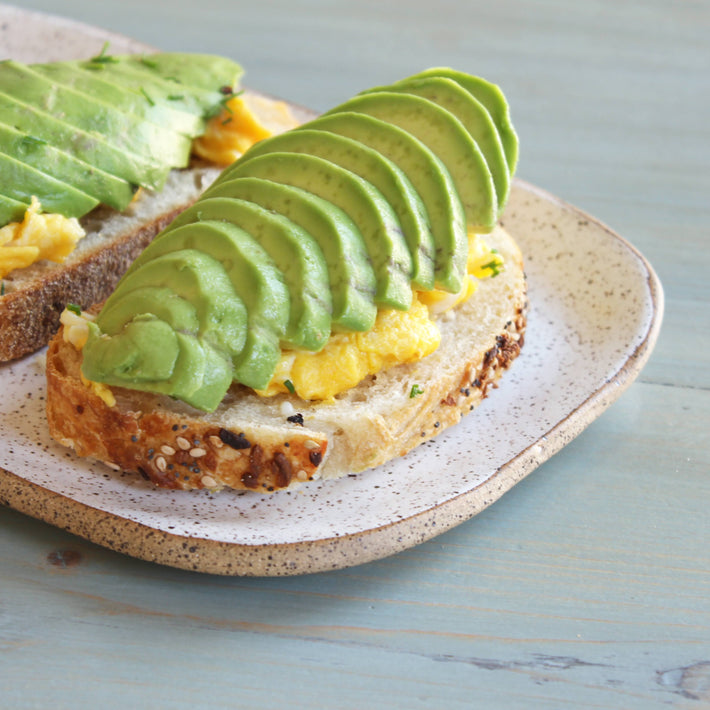 Sliced avocado on sourdough bread with scrambled eggs