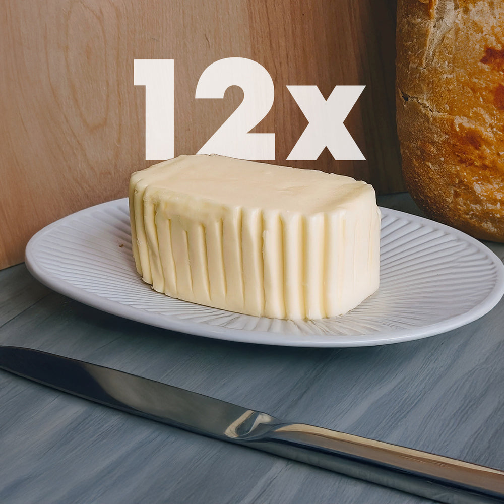 Stick of ridged butter on a white plate with a knife and a loaf nearby, overlaid text "12x"