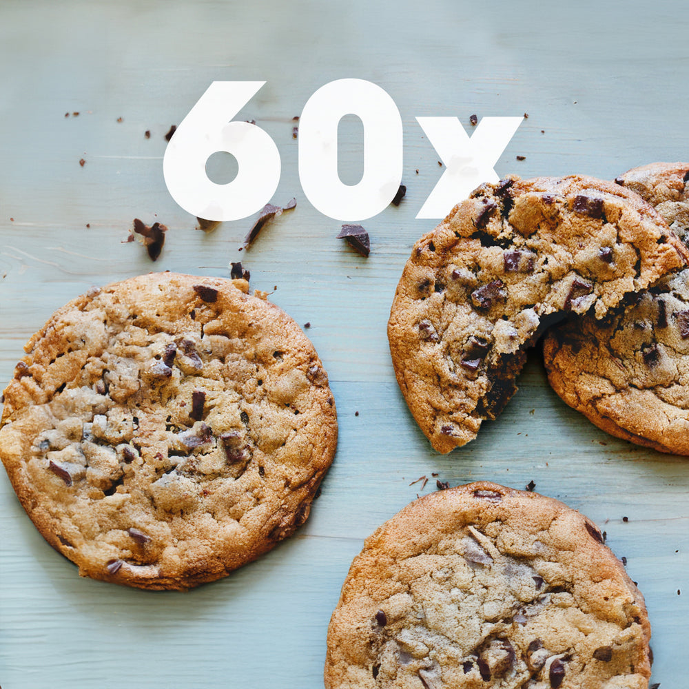 60x overlay above three chocolate-chip cookies on pale blue wooden board