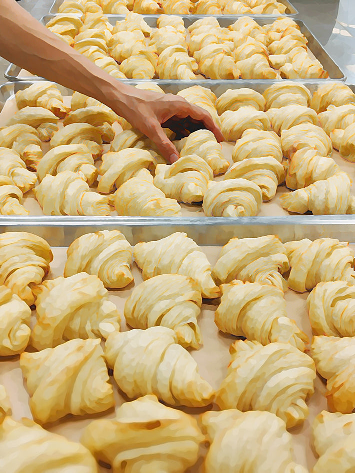 A tray of flaky plant-based croissants being handled