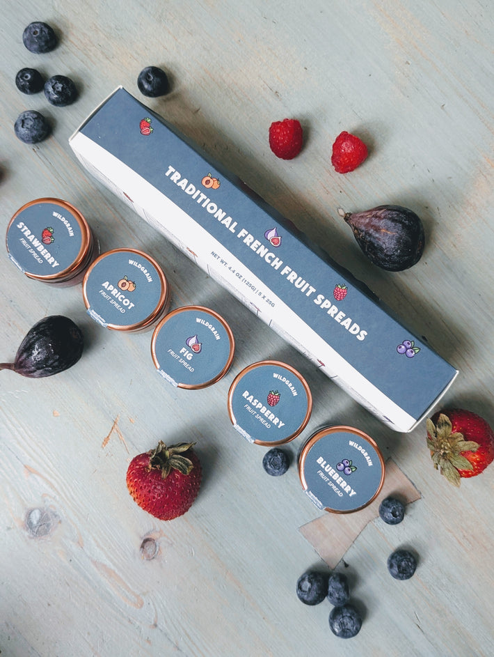 Overhead view of Traditional French Fruit Spreads five pack showcasing five fruit flavors with fresh berries on wood