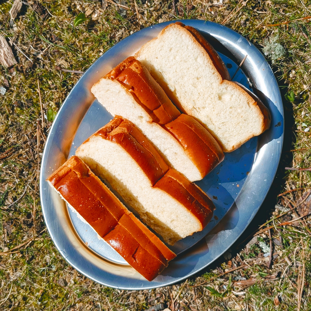 Top-down view of Slow-Fermented Hot Dog Buns (8-pack) showcasing sliced buns on a metal plate outdoors