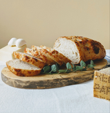 Sliced view of Sourdough 3-Cheese Loaf showing interior, with mozzarella and peppered cheese on a wooden board