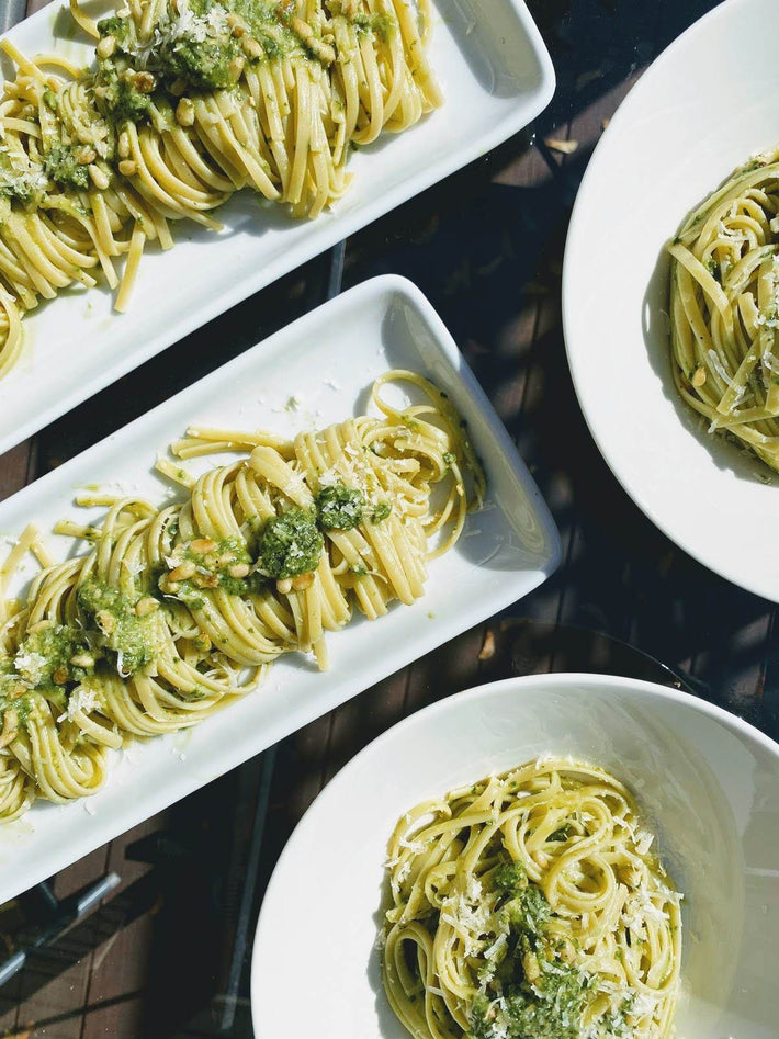 Plates of fresh Tonnarelli pasta topped with pesto and cheese