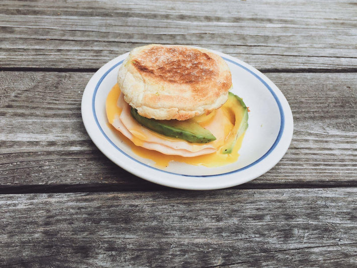 English muffin sandwich with turkey and avocado on a plate