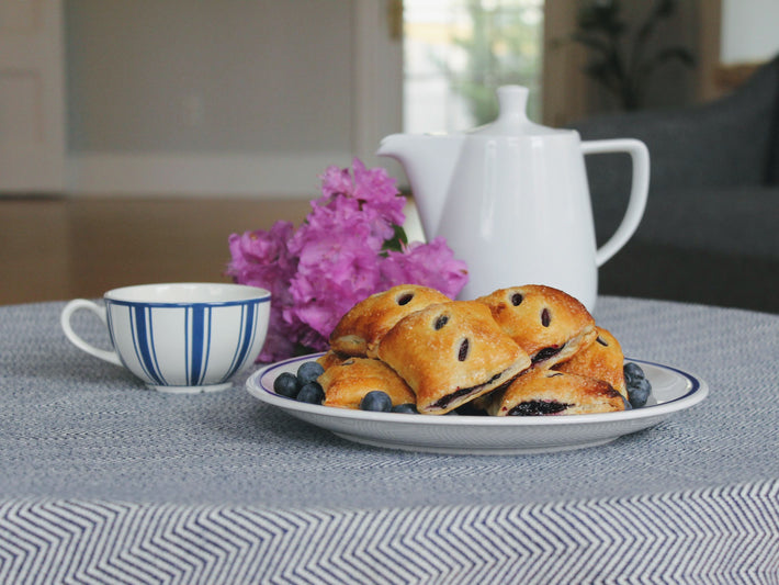 Blueberry Pie Bites on a plate with a cup of tea and flowers