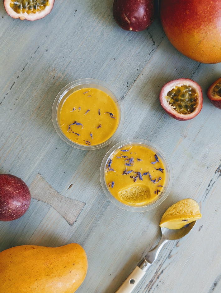 Mango & Passion Fruit Mousse in cups with passion fruits and mango on a table