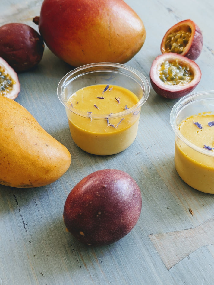 Mango and Passion Fruit Mousse in cups with mangoes and passion fruits on a table